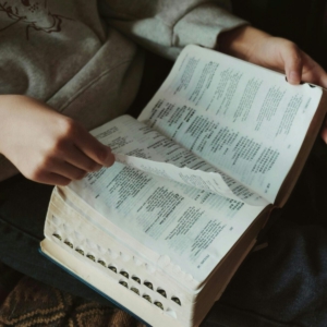 A person flipping through pages of a book, capturing a moment of thoughtful reading indoors.