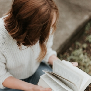 woman sitting on concrete floor reading book