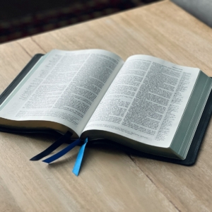 an open book on a table with a blue ribbon