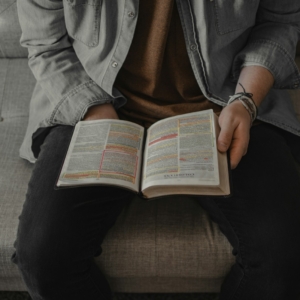 person in gray denim jacket reading book